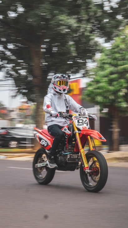 a man riding a red motorcycle down a street