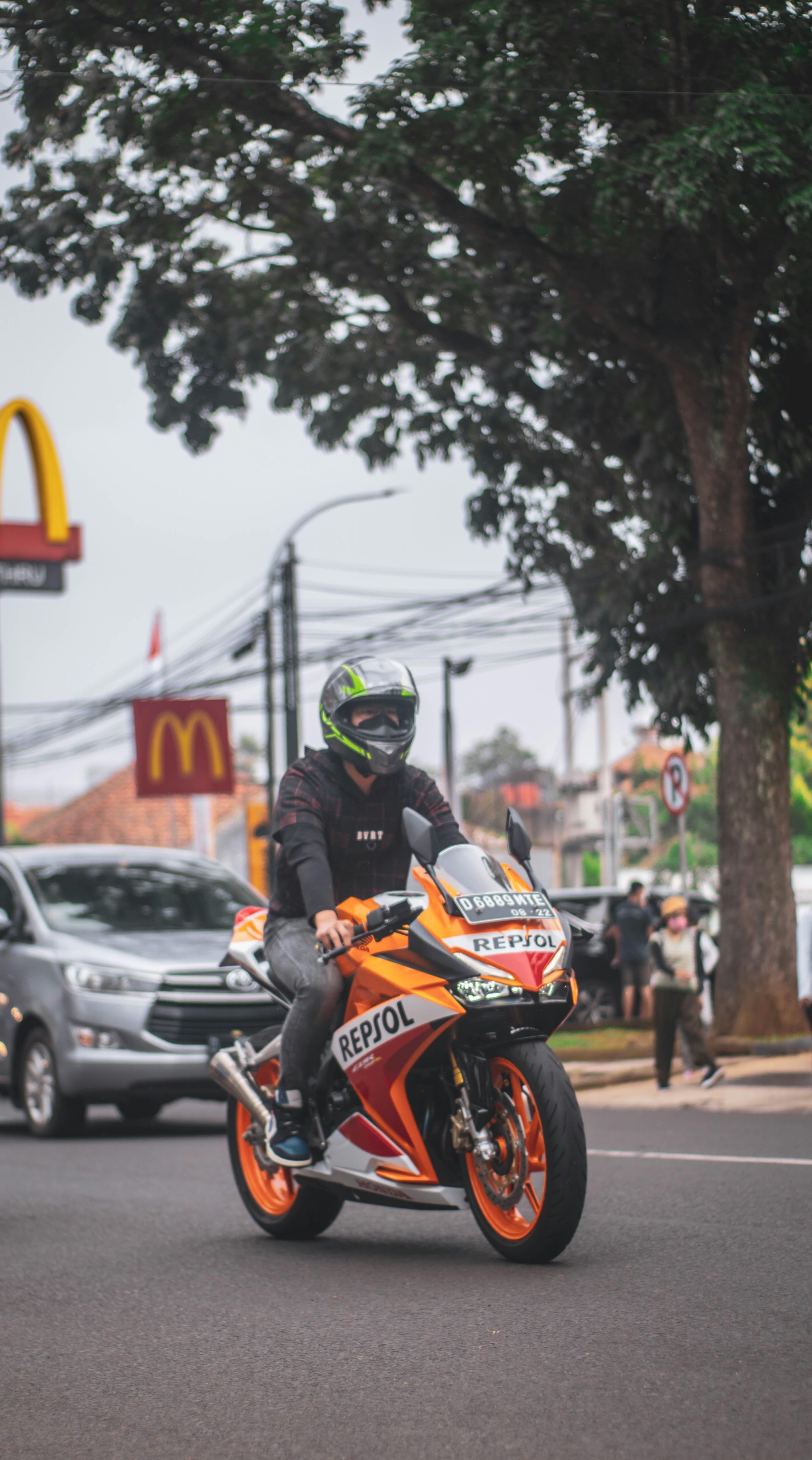 Seorang pria mengendarai sepeda motor di jalan