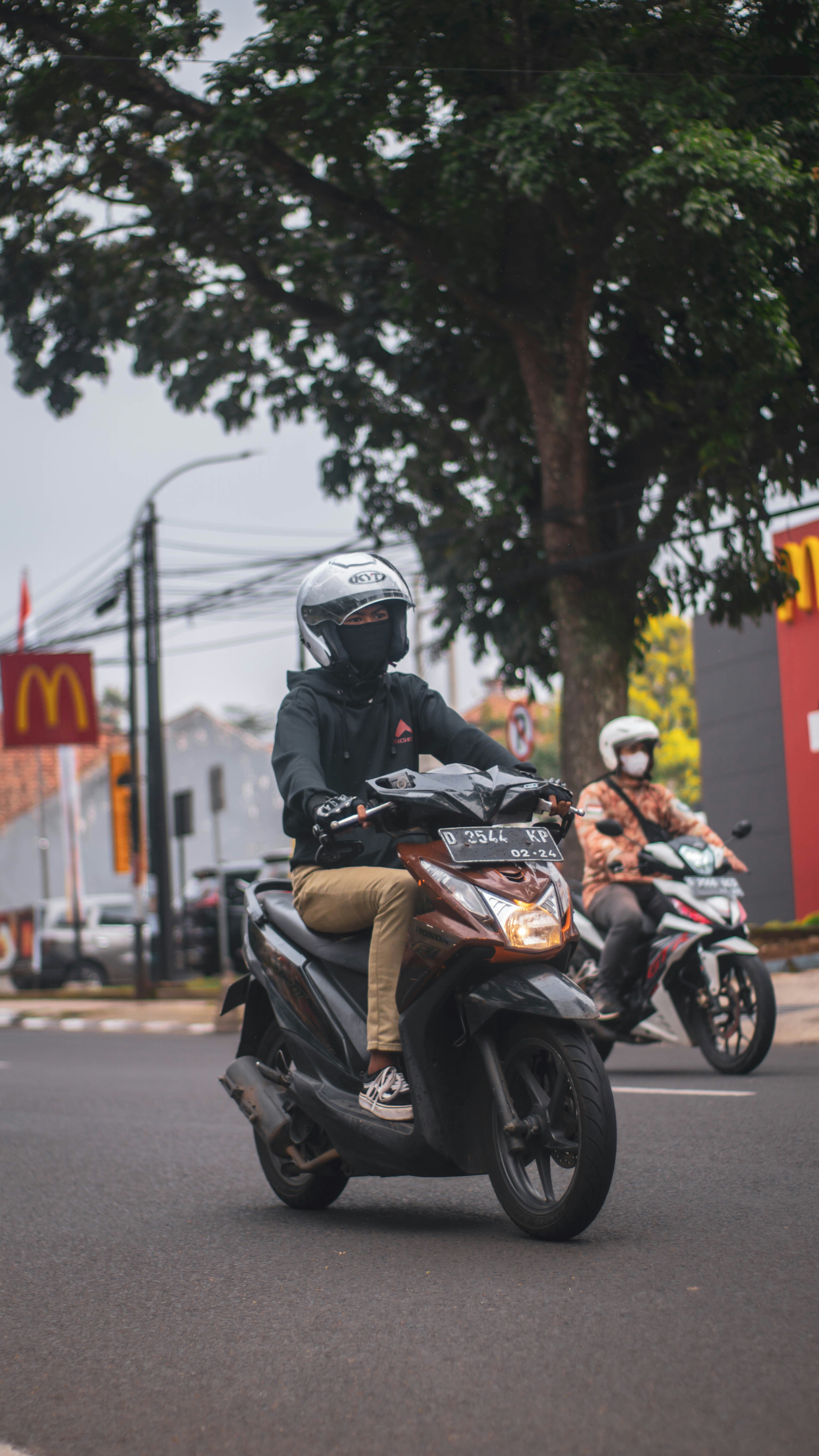 Seorang pria mengendarai sepeda motor di jalan