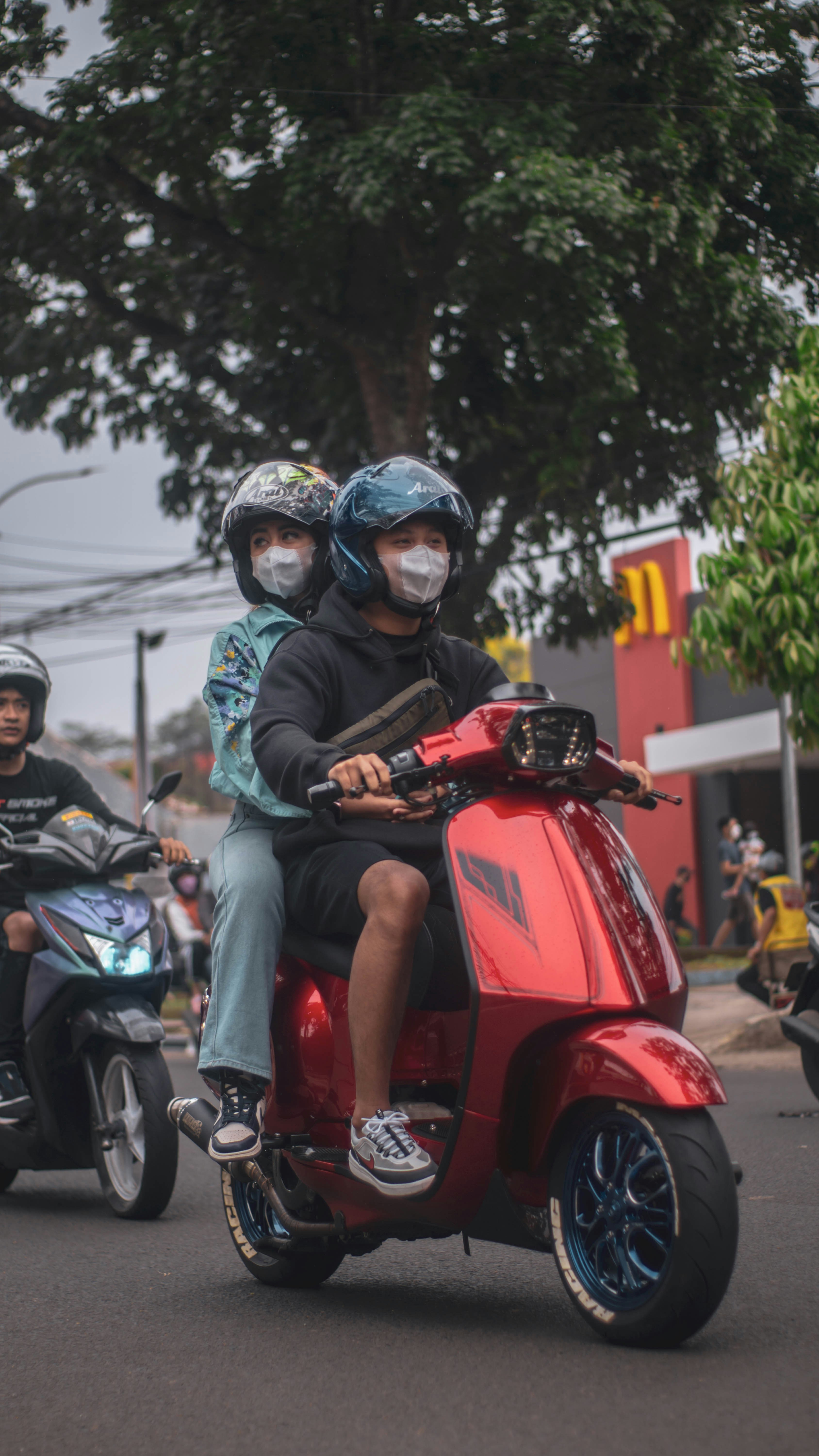 Beberapa orang mengendarai bagian belakang skuter merah