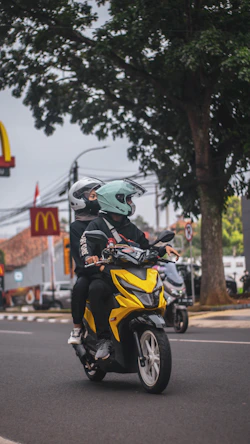 a man riding a yellow motorcycle down a street