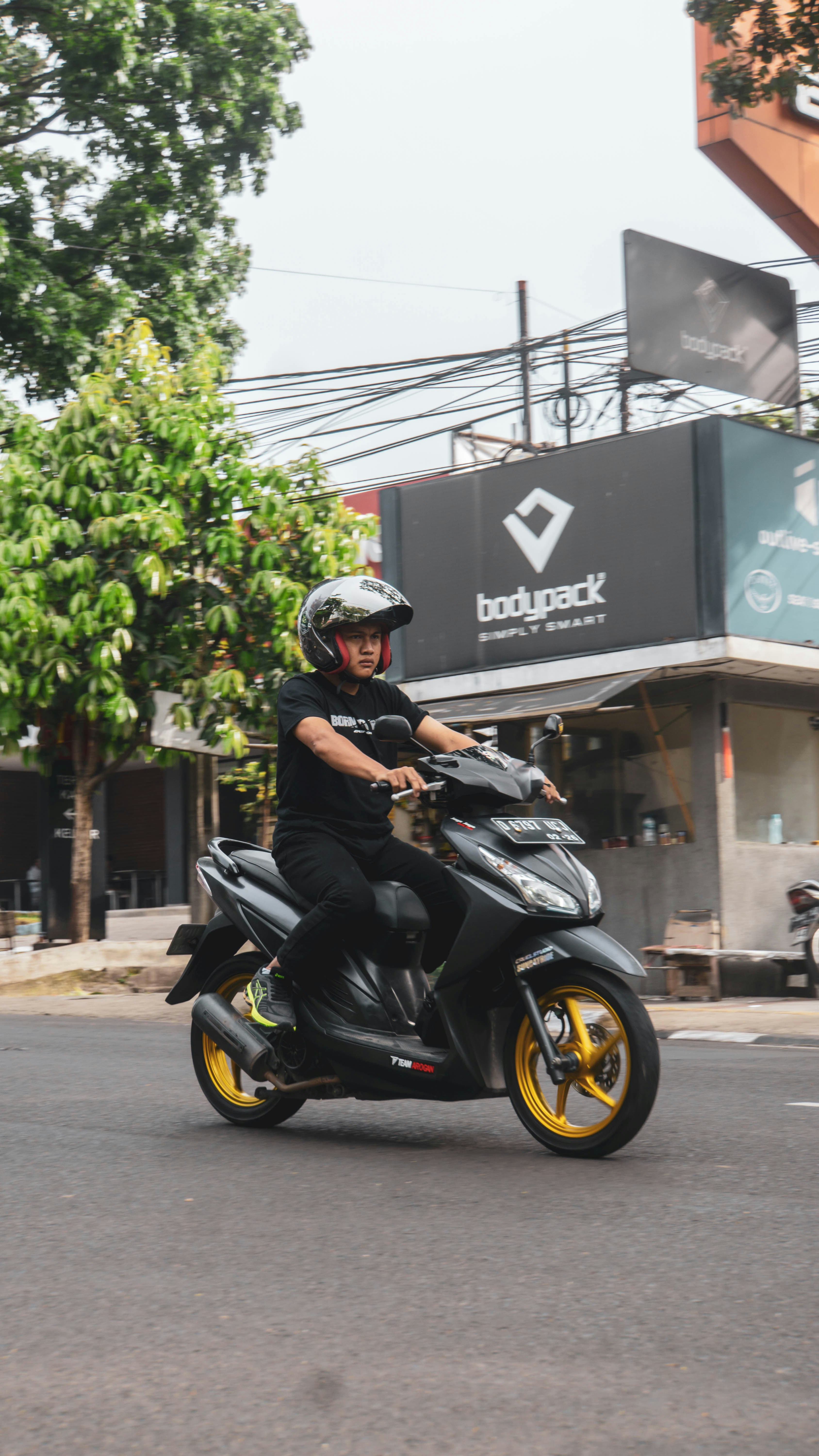 Seorang pria mengendarai sepeda motor di jalan