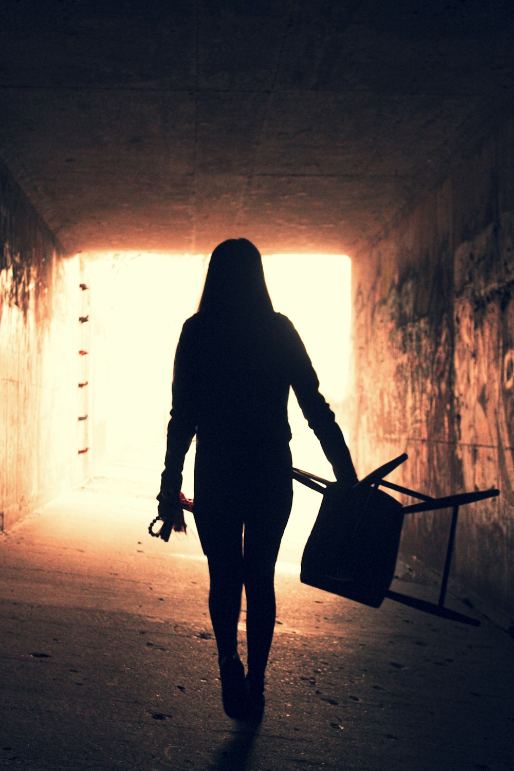 a woman walking through a tunnel carrying a suitcase