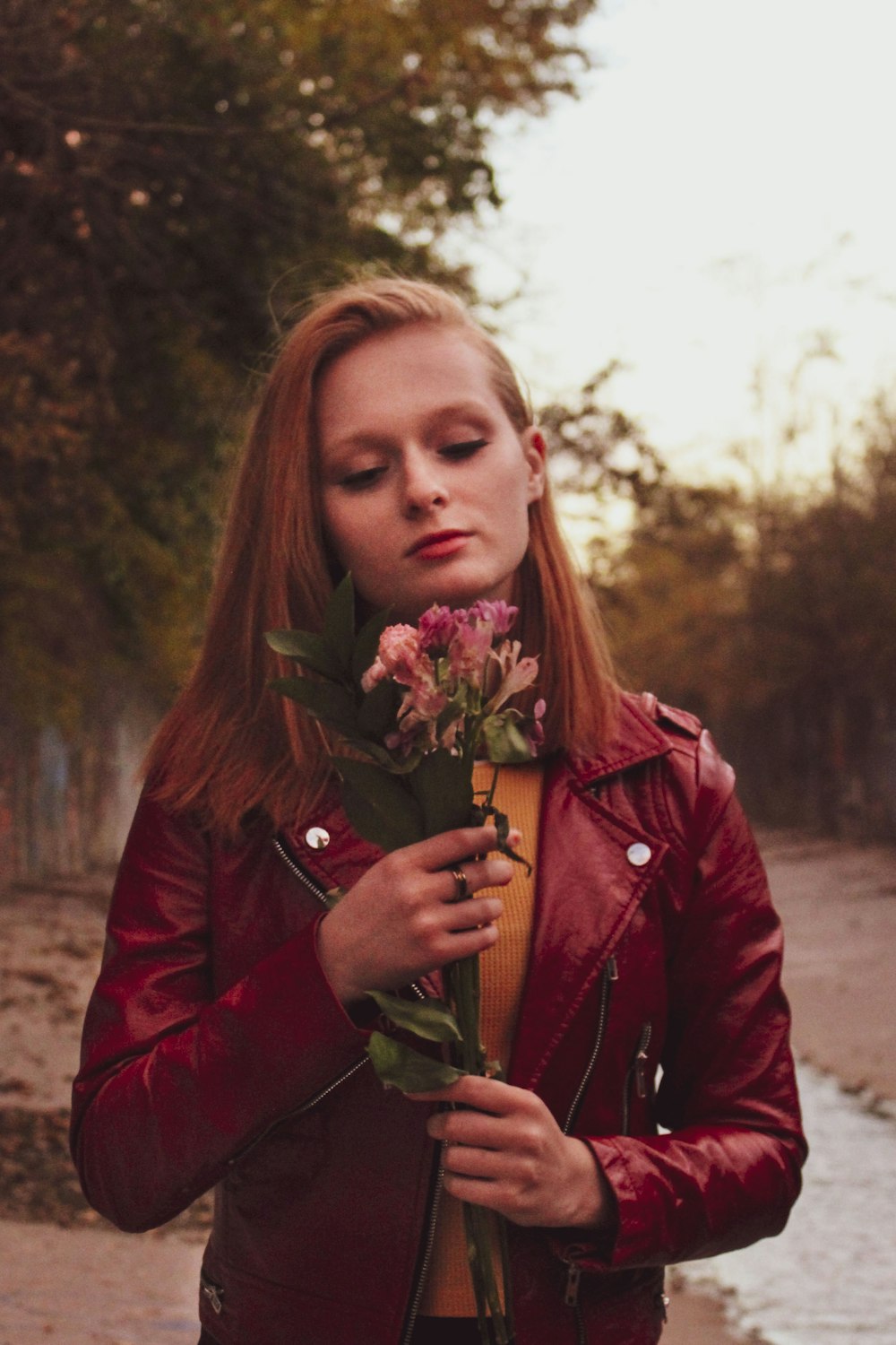a woman in a red jacket holding a flower