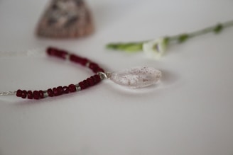Close-up of a delicate flower necklace combining red and coffee tones with a vintage feel.
