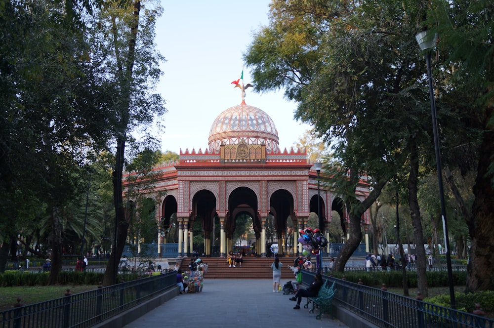 a gazebo surrounded by trees and people sitting on benches