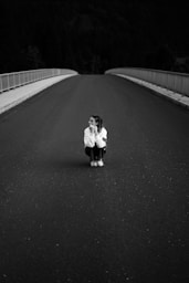 a woman kneeling down on the side of a road