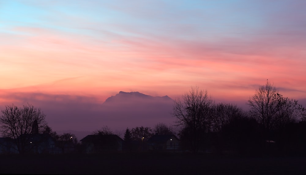 a pink and blue sky with a mountain in the distance