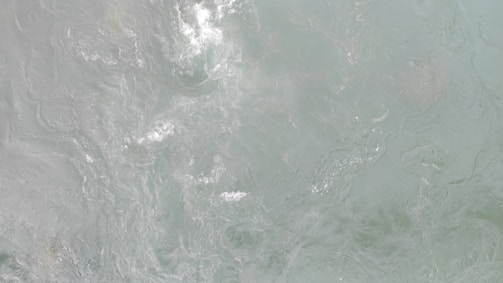 Rippling water with gentle, swirling patterns, creating a dynamic and fluid texture.