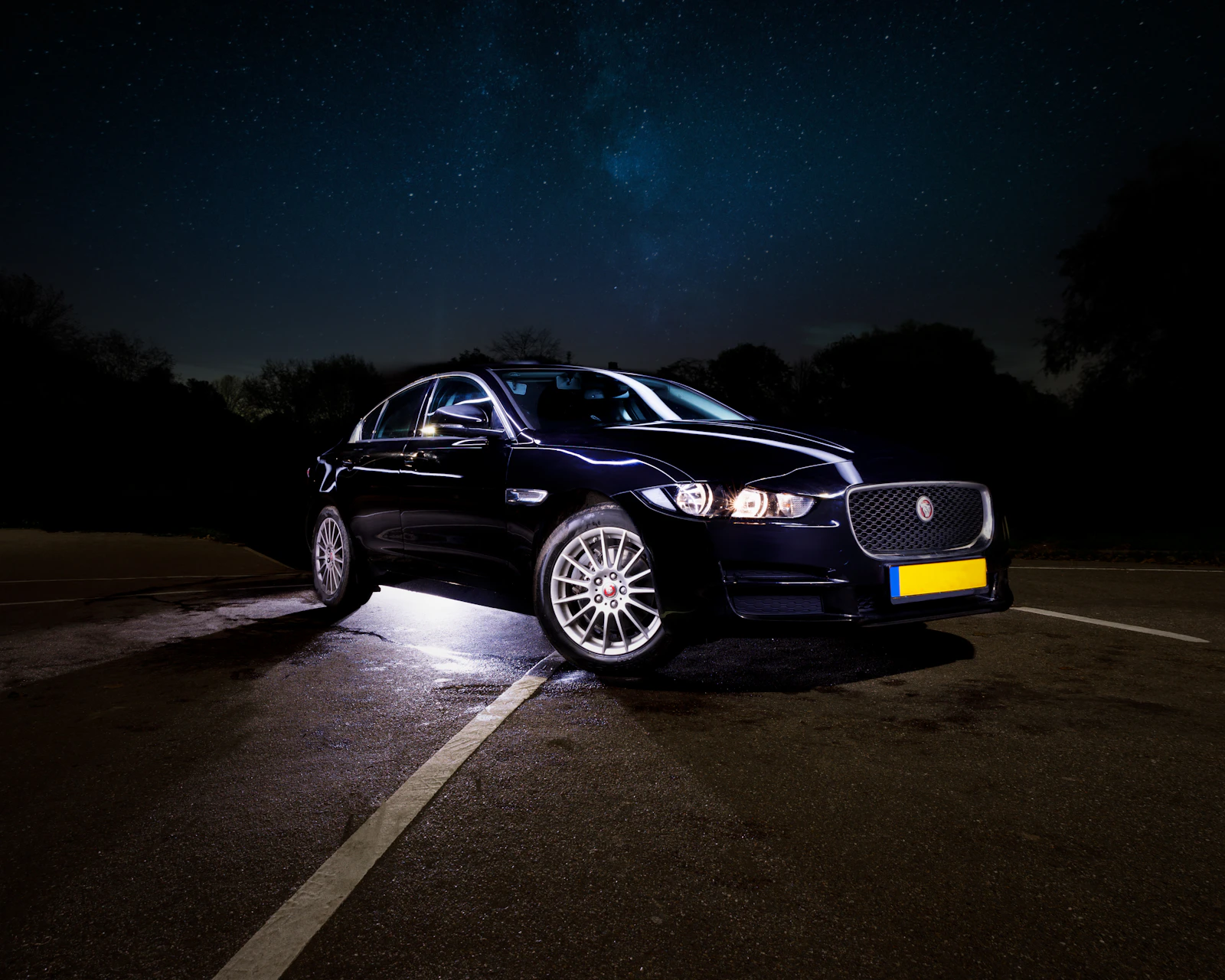 A black car waiting under city lights at night