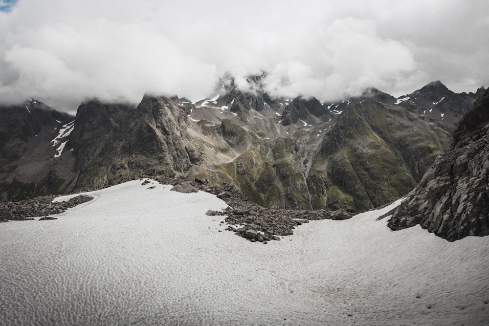 a snow covered mountain range with clouds in the sky