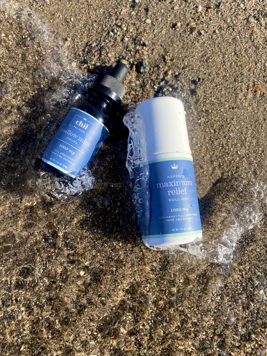 Recovery Roll-On beside a tincture bottle, sitting in wet sand
