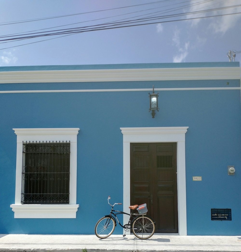 Ein Fahrrad, das vor einem blauen Gebäude geparkt ist