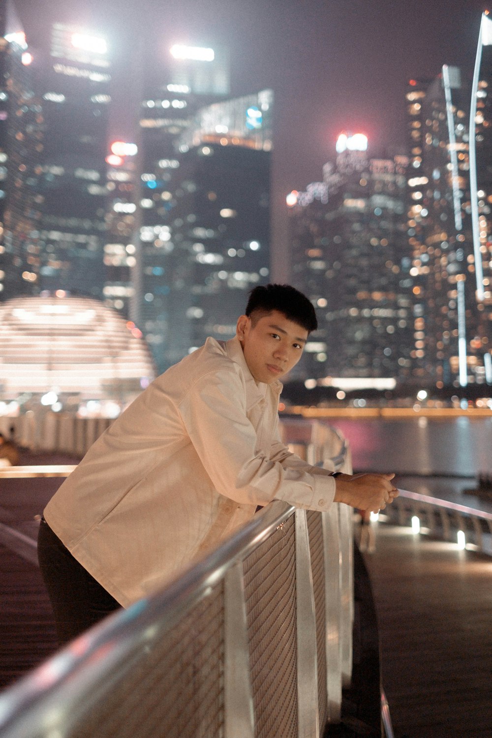 a man leaning on a railing in front of a city skyline