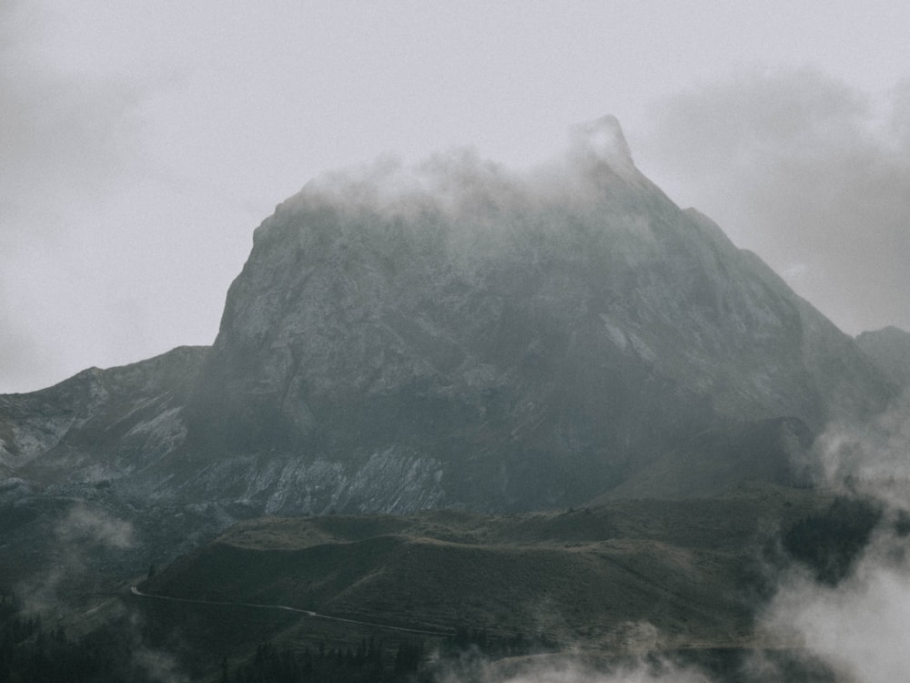 a mountain covered in fog and clouds on a cloudy day