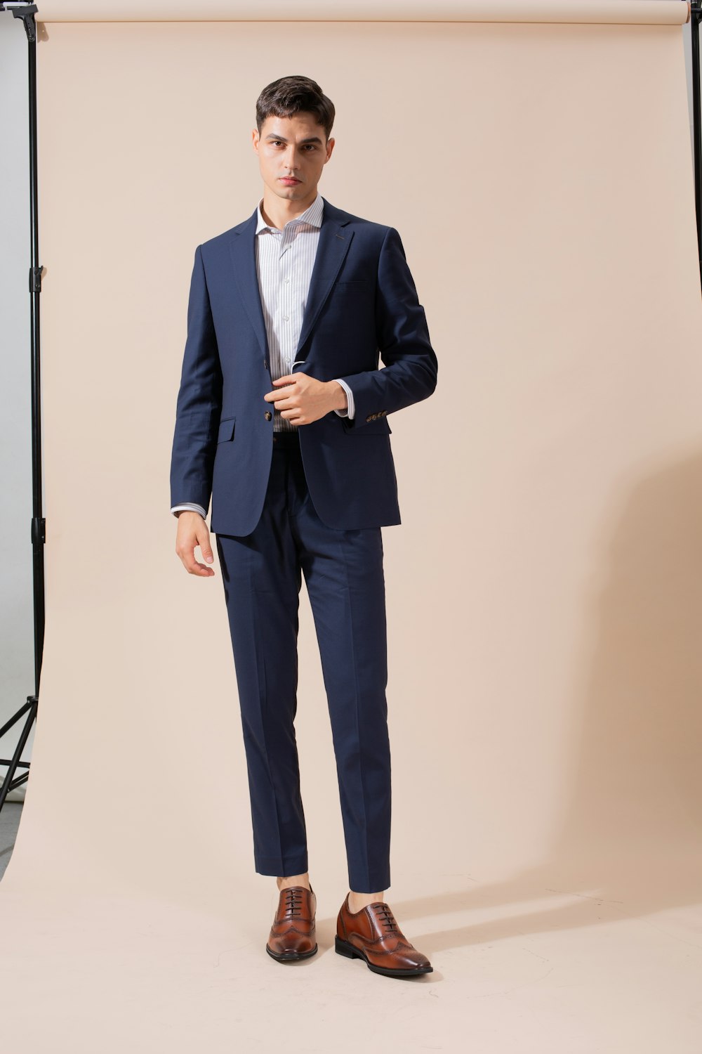 a man in a blue suit stands in front of a backdrop