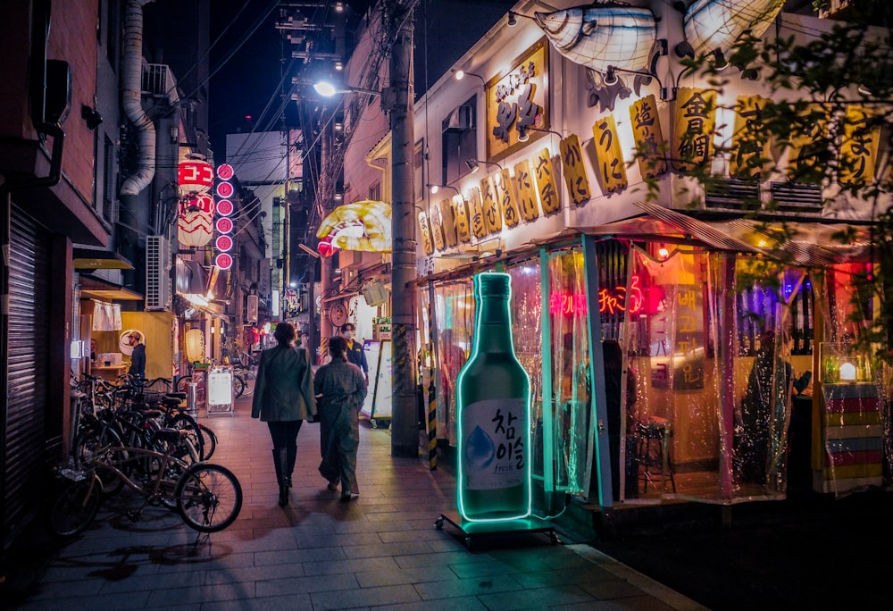 a couple of people walking down a street at night