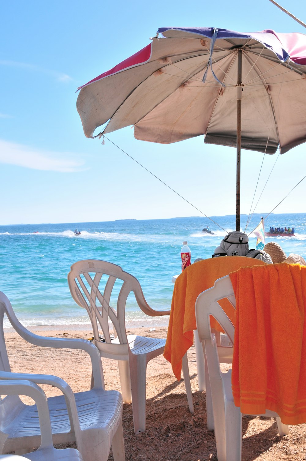 Una silla de playa con sombrilla y una silla de playa en la arena.