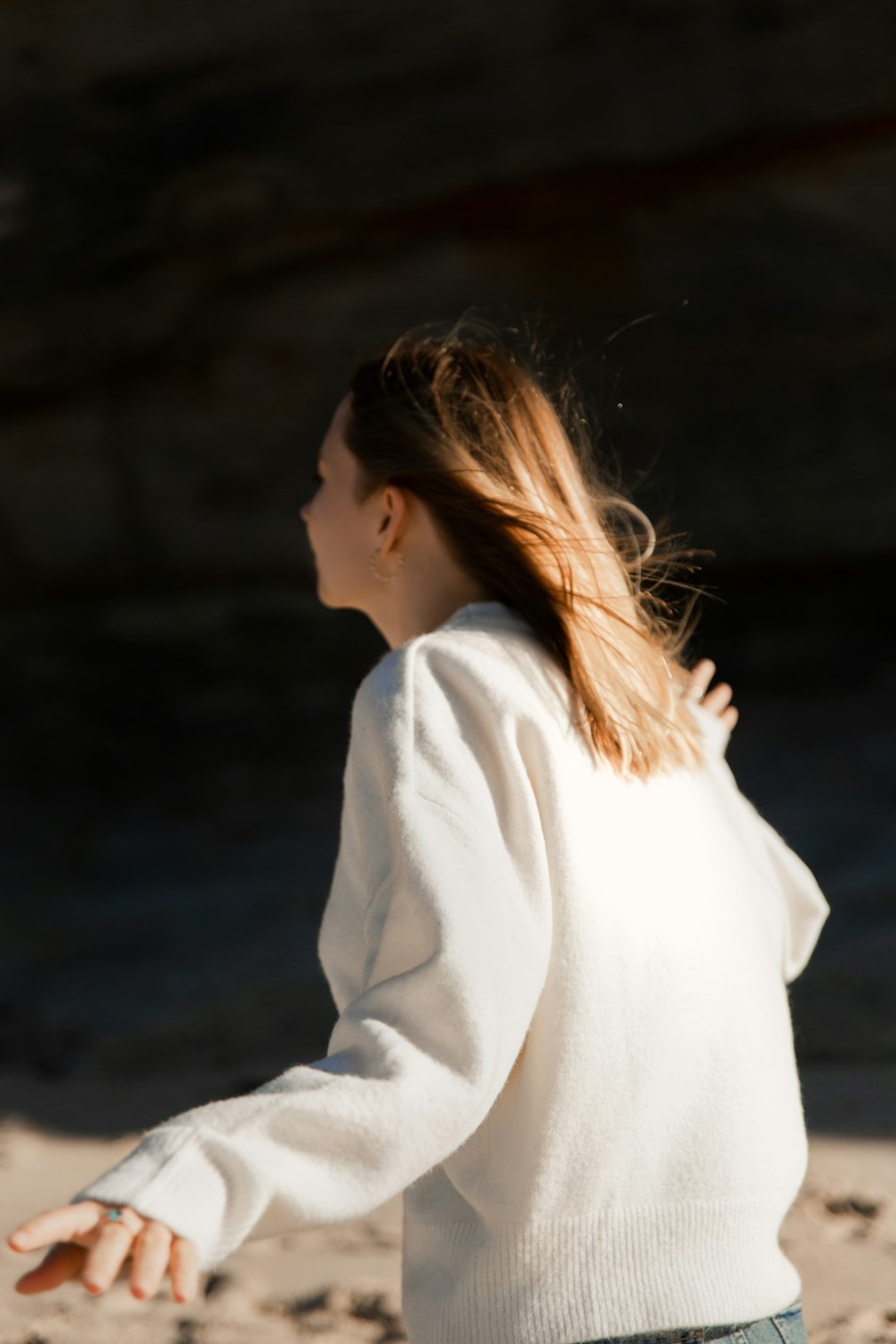 a woman in a white sweater throwing a frisbee