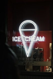 a neon ice cream sign in the window of a store