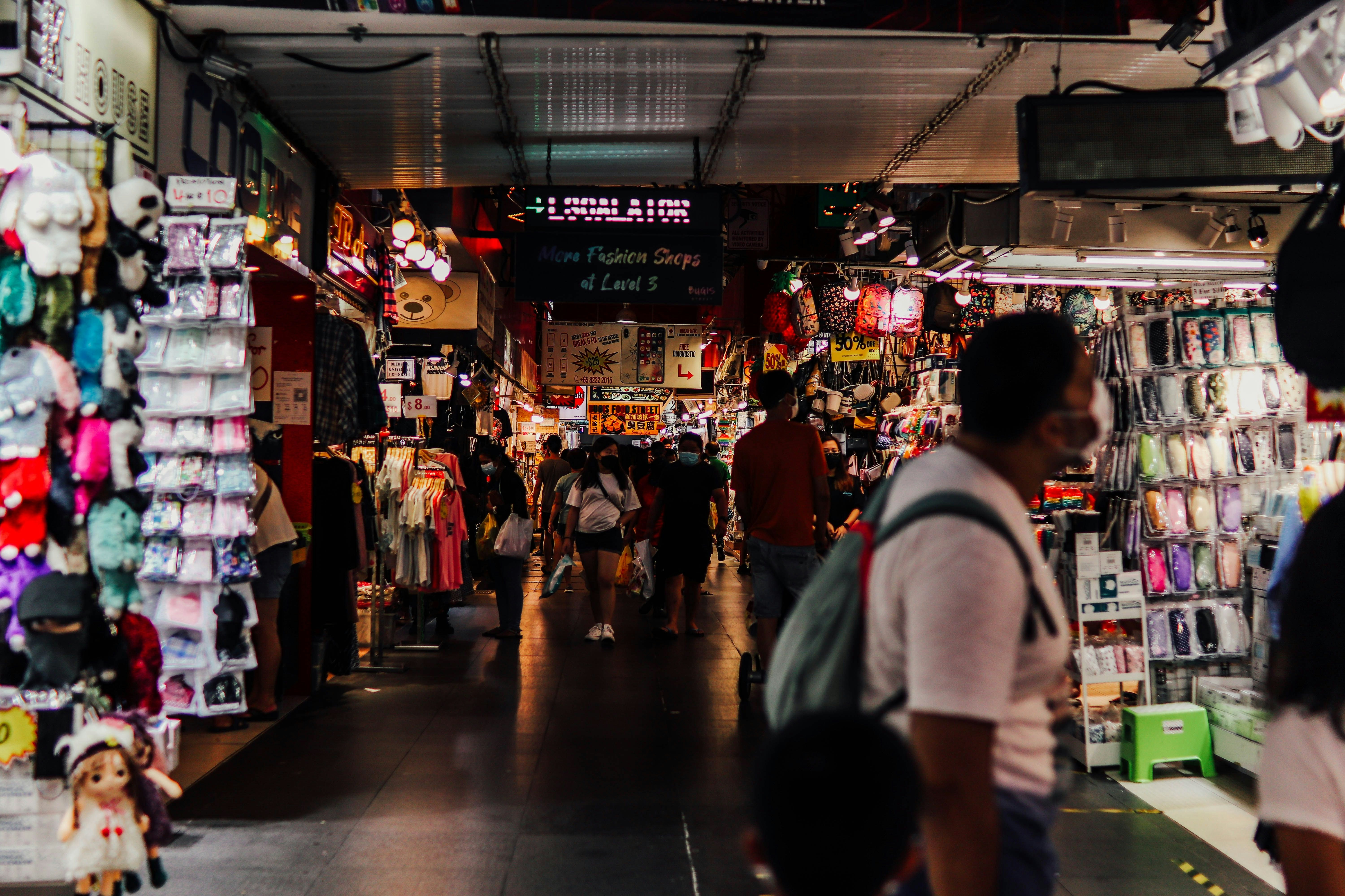 a group of people walking through a store filled with items