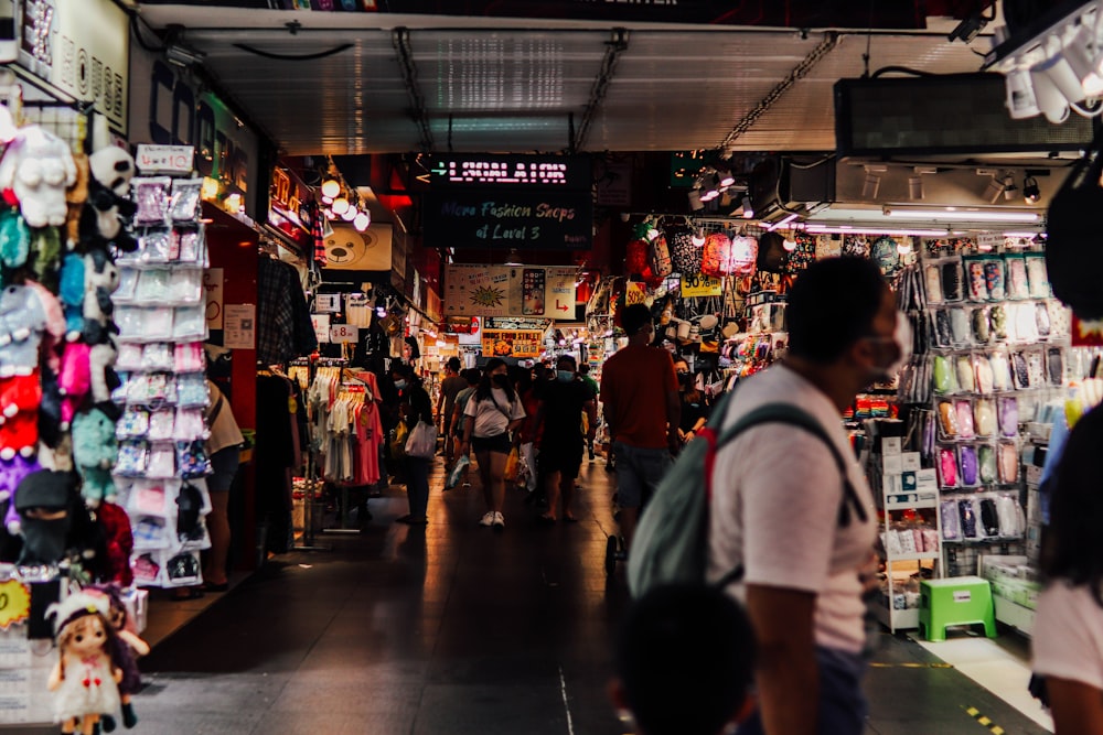 a group of people walking through a store filled with items