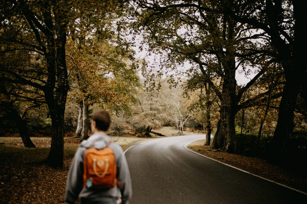 a person walking down a street next to a tree