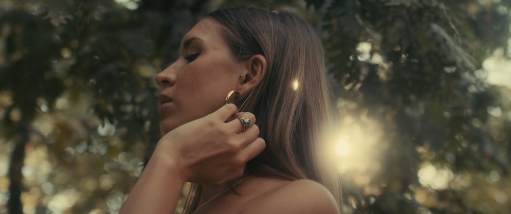 a woman standing in front of a tree with a ring on her finger