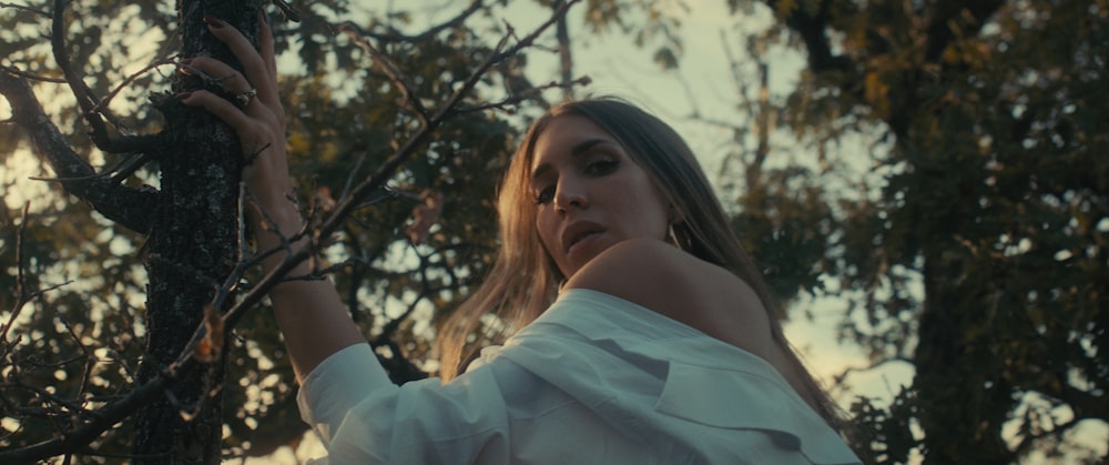 a woman in a white shirt is holding a branch