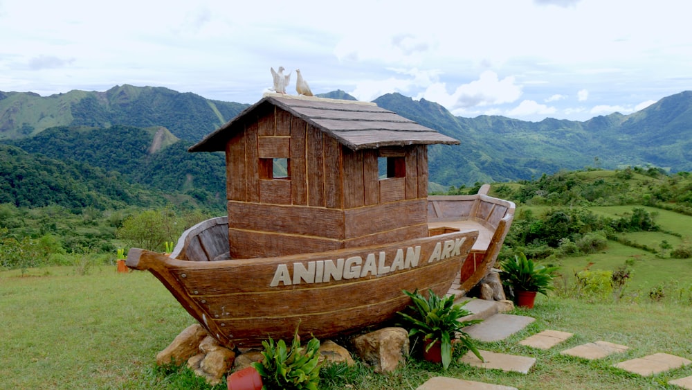 a wooden boat sitting on top of a lush green hillside