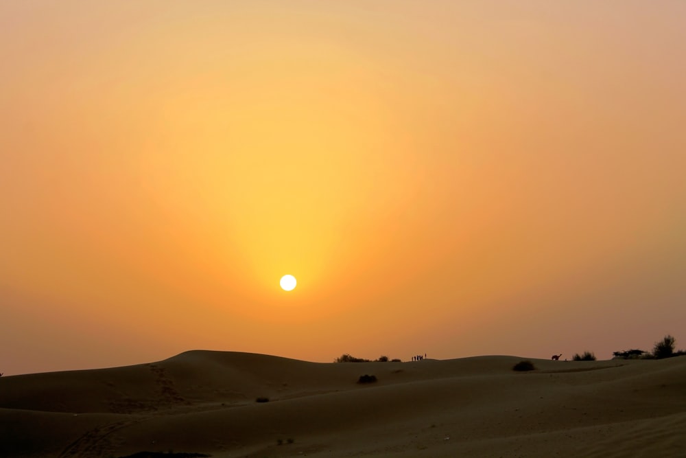 Il sole sta tramontando nel cielo sopra il deserto