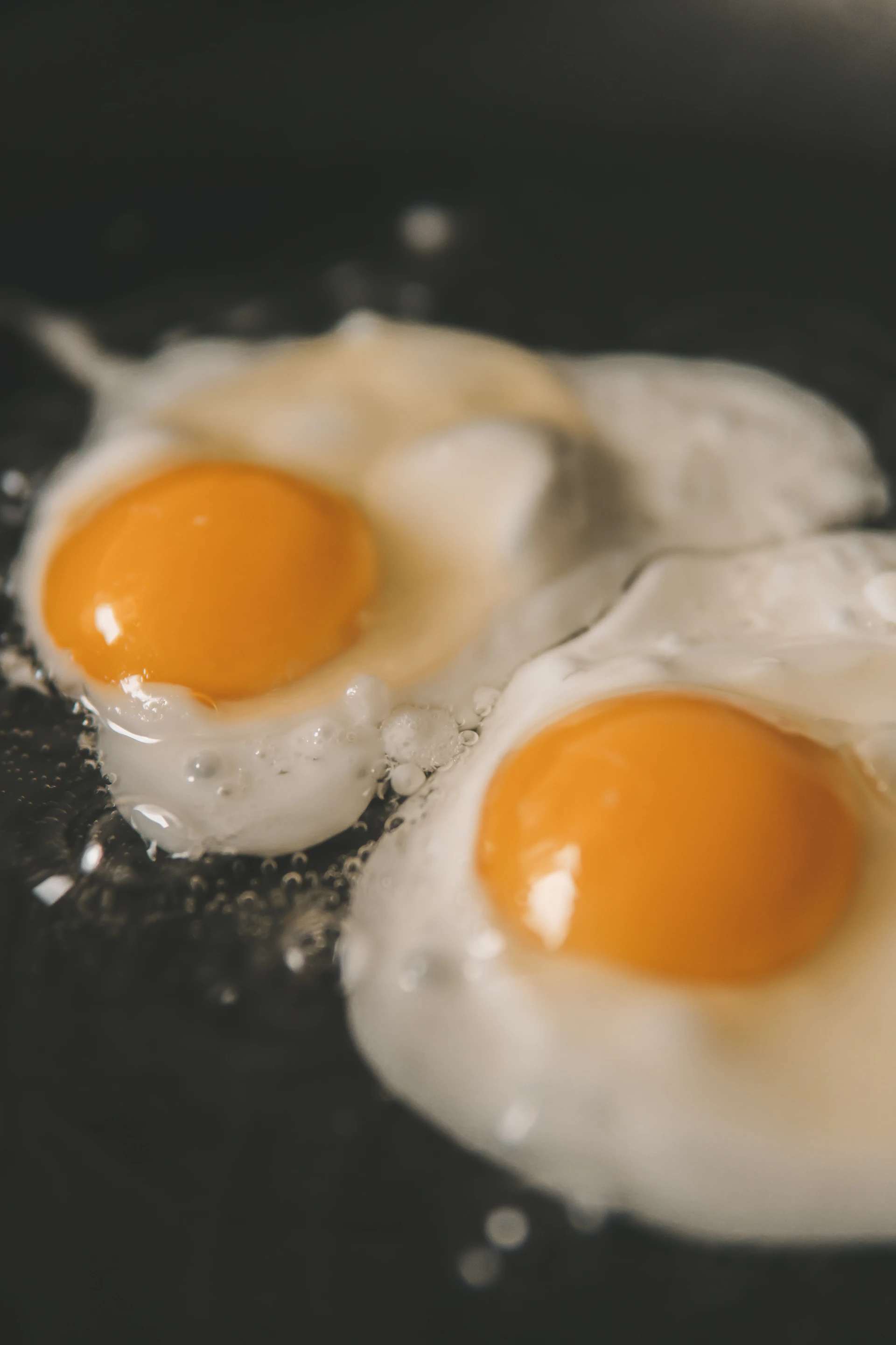 two eggs frying in a frying pan on a stove