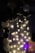 An arrangement of black and white balloons is displayed next to string lights hanging on a vertically striped backdrop. The lights emit a soft warm glow, highlighting the balloons and creating a festive atmosphere.