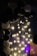 An arrangement of black and white balloons is displayed next to string lights hanging on a vertically striped backdrop. The lights emit a soft warm glow, highlighting the balloons and creating a festive atmosphere.