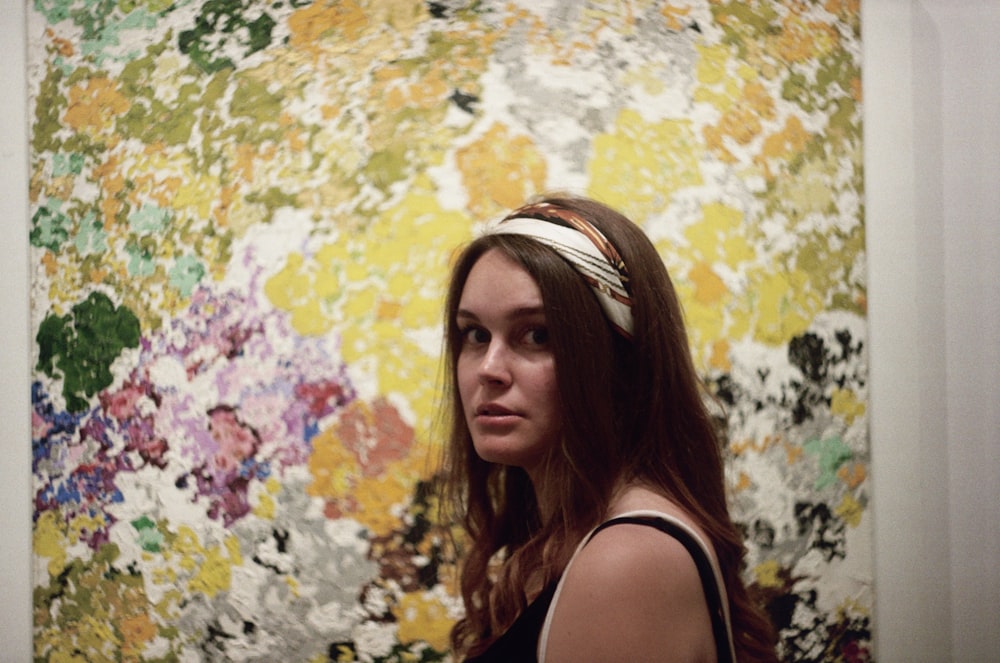 a woman standing in front of a colorful painting
