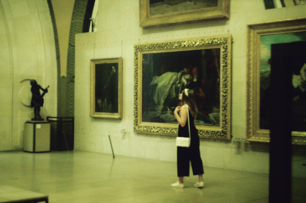 a woman taking a picture of a painting in a museum