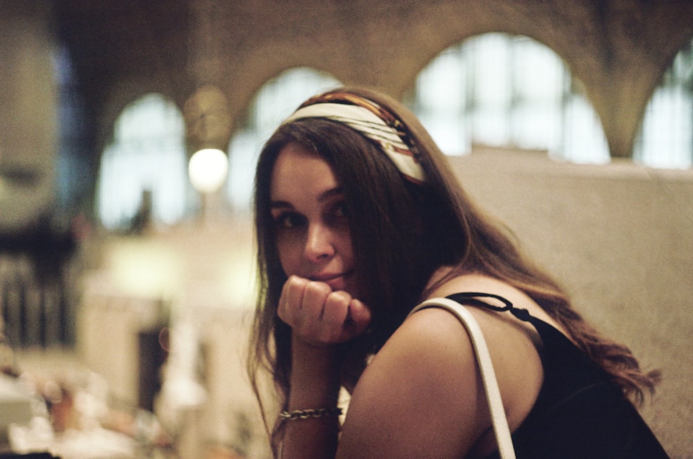 a woman sitting on a bench with her hand on her chin