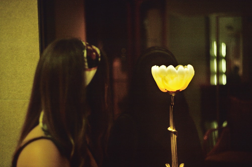 a woman standing in front of a yellow flower