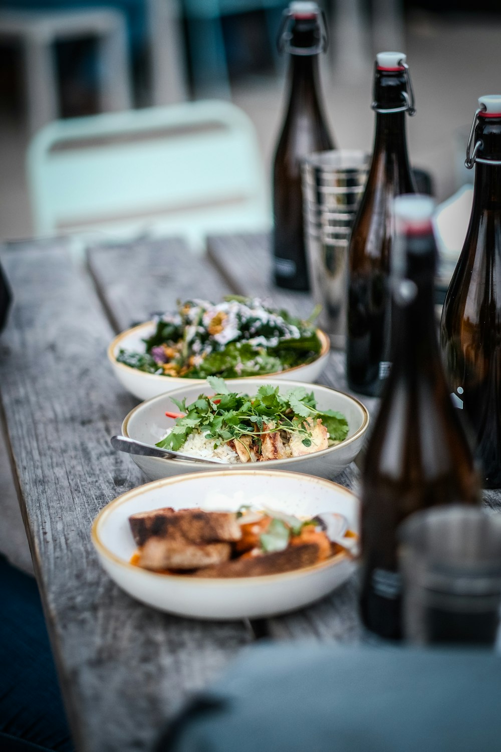 a wooden table topped with plates of food and bottles of beer