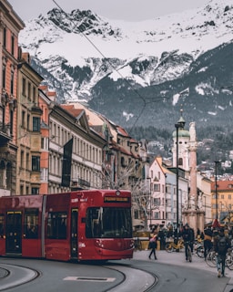 a red bus driving down a street next to tall buildings