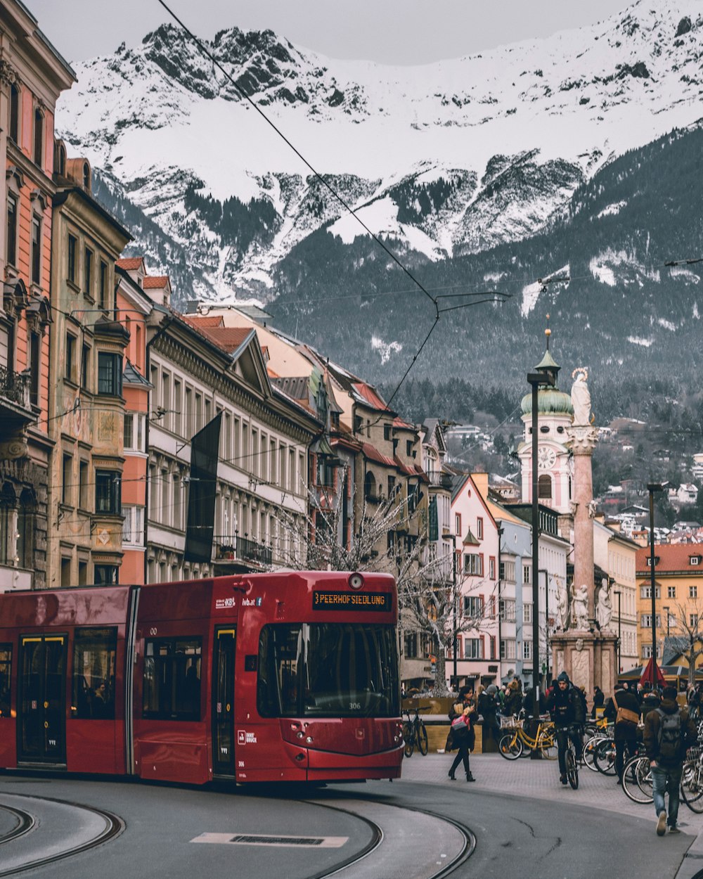 Ein roter Bus fährt eine Straße neben hohen Gebäuden entlang