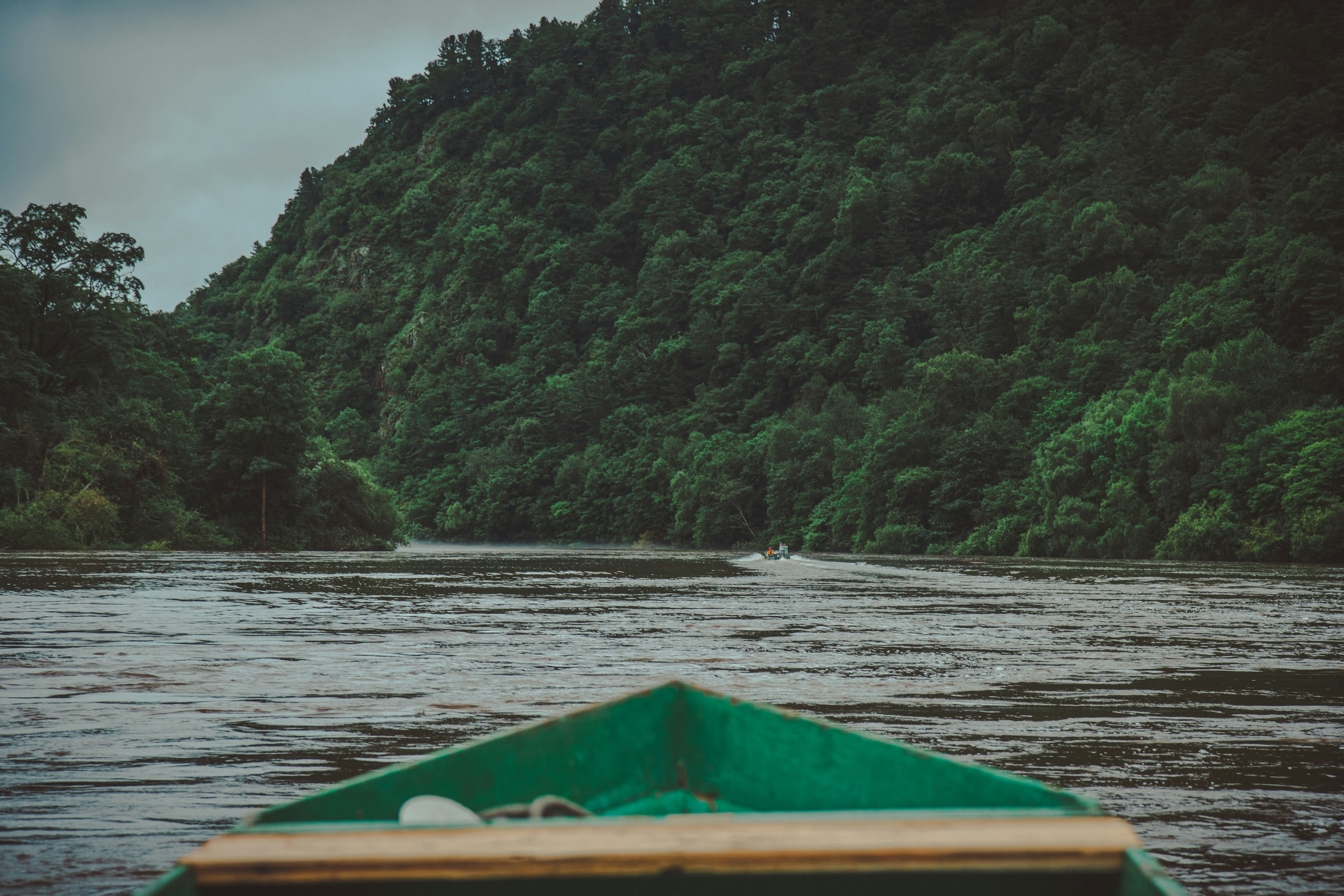 a green boat floating on top of a river