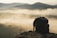 Photo of a weathered hemp backpack resting against a rocky trail with the Himalayas in the misty background.