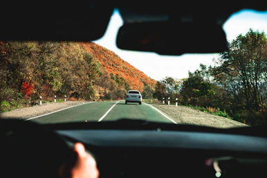 a car driving down a road with a mountain in the background