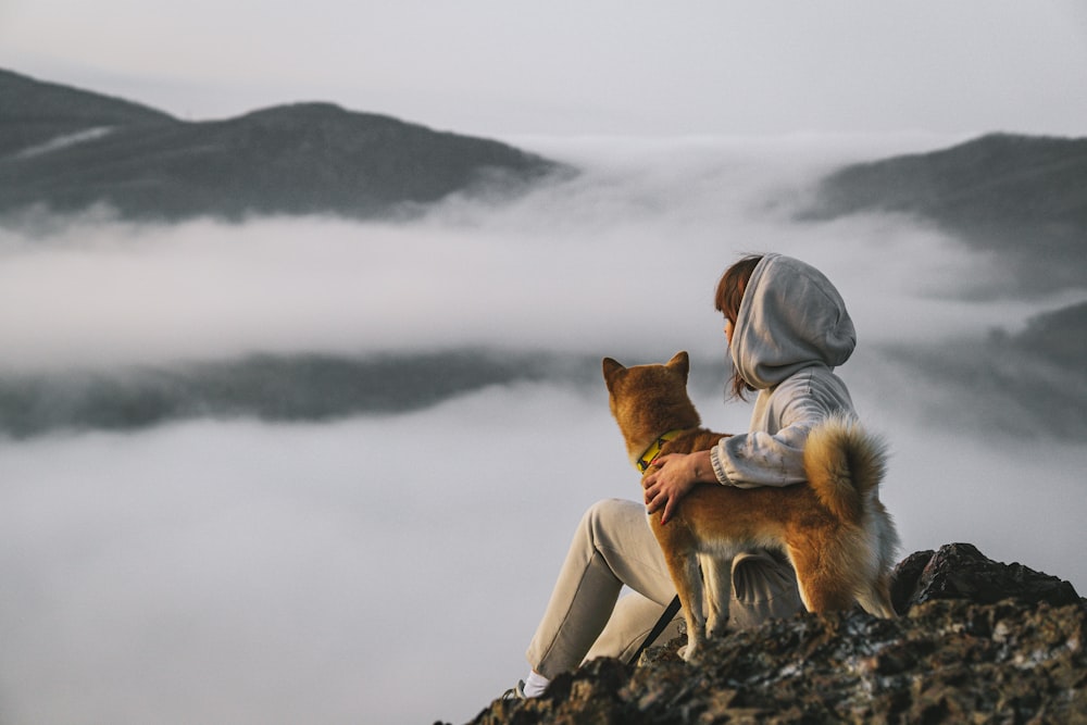 Ein Mann, der mit einem Hund auf einem Berg sitzt