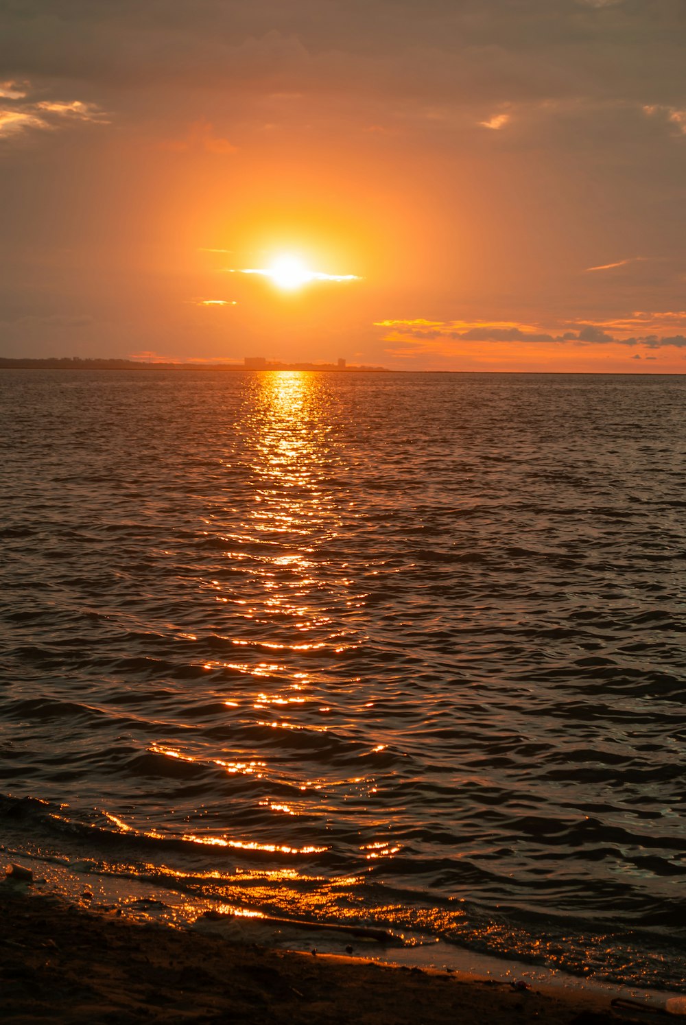 the sun is setting over the ocean on a cloudy day