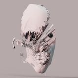 An abstract three-dimensional digital artwork with jagged, fragmented textures and a neutral background. The central form resembles a distorted face, characterized by sharp, angular protrusions and a mix of smooth and rough surfaces. A small, round black object is embedded in the composition, adding contrast to the dominant light tones.