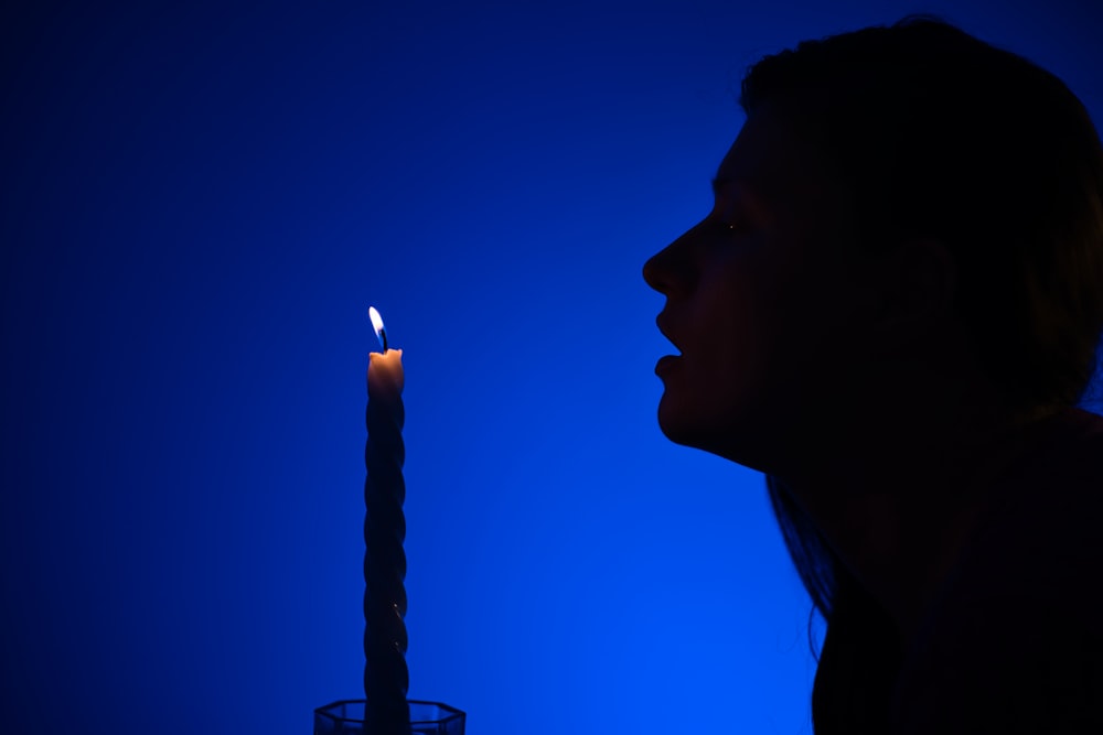 a woman standing in front of a lit candle