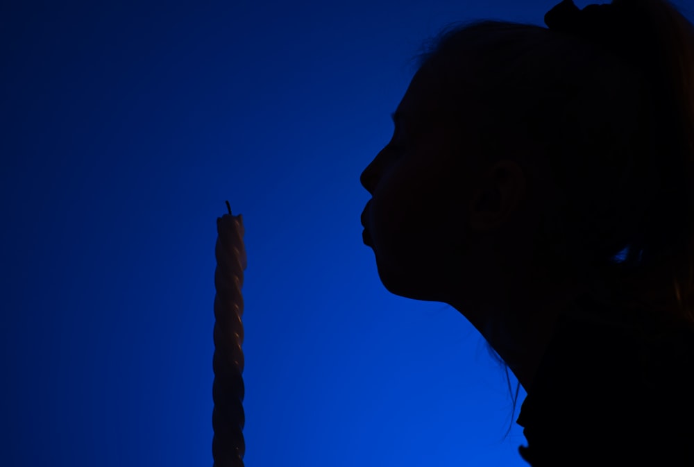 a silhouette of a woman holding a lit candle