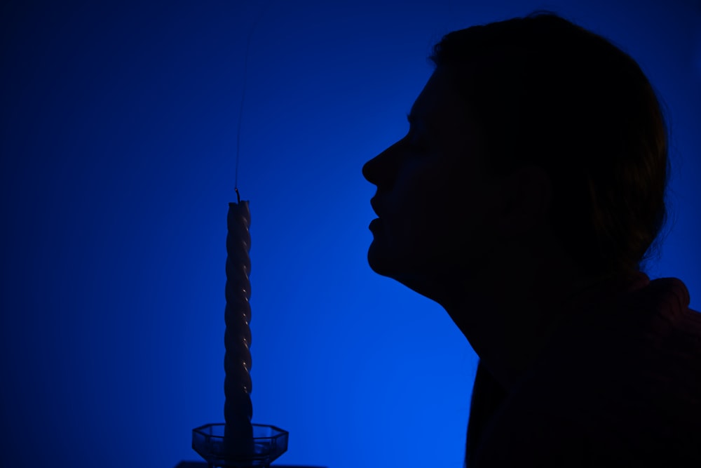 a person standing in front of a lit candle